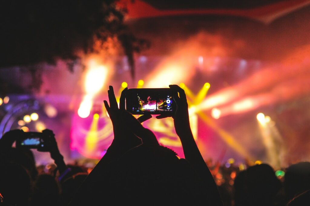 Hands holding a phone recording a video at a concert